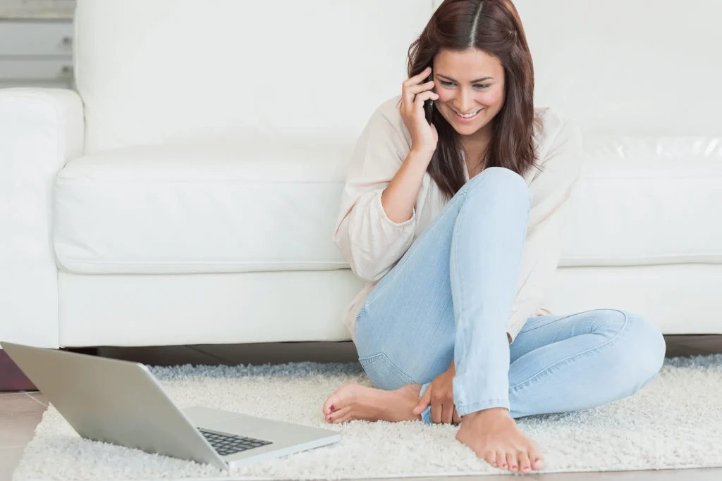 Woman sitting on a carpet and making a phone call.