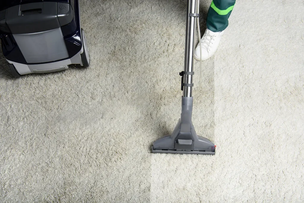 Technician using a shampooer to clean a white carpet.