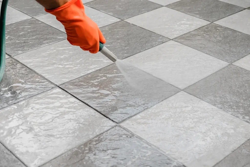 hand in orange glove rinsing stone flooring .