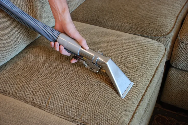 Hand vacuuming beige sofa